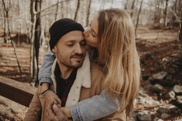 Girlfriend kissing on boyfriend's forehead in forest during autumn - GMLF01141