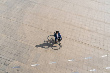 Mann fährt mit dem Fahrrad auf der Promenade und blickt an einem sonnigen Tag nach oben - AFVF08501