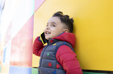 Smiling boy looking away while talking on mobile phone - JCCMF01801