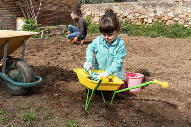 Verspieltes Mädchen bei der Gartenarbeit mit Vater im Hinterhof - GEMF04733