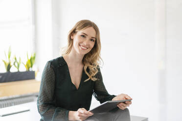 Schöne lächelnde Geschäftsfrau hält digitale Tablet im Büro - DIGF15014