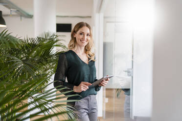 Lächelnde Unternehmerin mit digitalem Tablet im Büro - DIGF15023