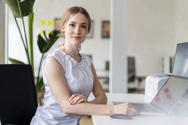 Weibliche Fachkraft sitzt vor einem Laptop im Büro - DIGF15036