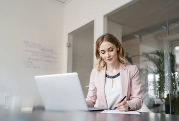 Female professional writing on document at conference table in office - DIGF15045