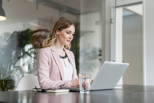 Berufstätige Frau arbeitet am Laptop am Schreibtisch - DIGF15047