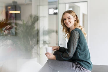 Zufriedene weibliche Fachkraft beim Kaffee im Büro - DIGF15069