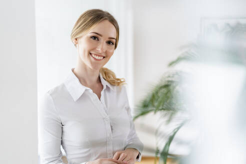 Glückliche Geschäftsfrau im Büro stehend - DIGF15088