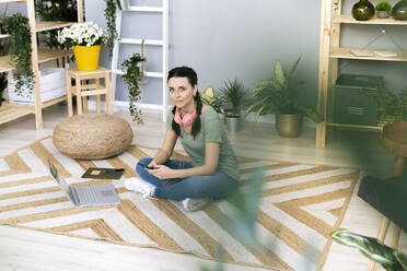 Frau sitzt zu Hause auf Teppich - GIOF12121