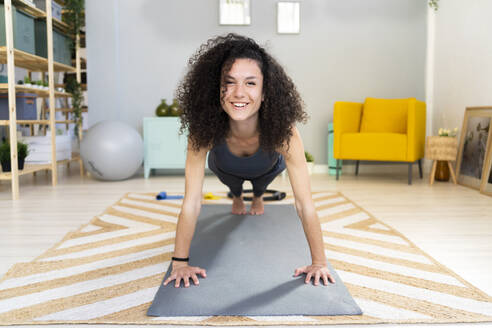 Smiling beautiful woman doing push-ups at home - GIOF12144