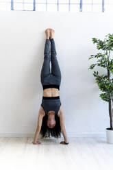 Woman doing handstand at home - GIOF12175