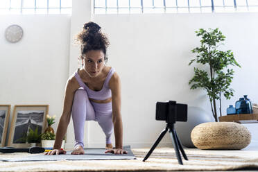 Female vlogger filming while practicing yoga at home - GIOF12177