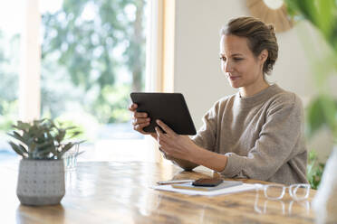 Businesswoman using tablet while sitting at table - SBOF03732