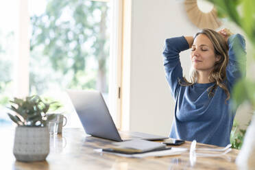 Relaxed female professional sitting with eyes closed while taking break from work at home - SBOF03740