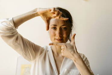 Beautiful woman making finger frame at home - VABF04312