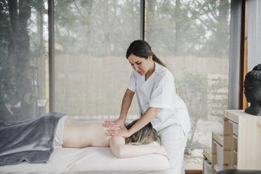 Female physiotherapist in uniform massaging patient in hospital - EBBF03241