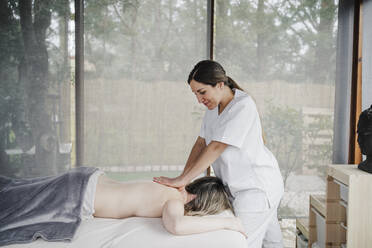 Smiling physiotherapist massaging patient in clinic - EBBF03242