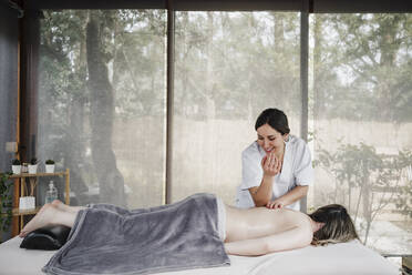 Smiling female physiotherapist massaging patient with elbow in clinic - EBBF03243