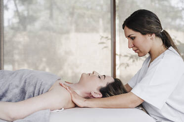 Female physical therapist massaging patient's shoulder in hospital - EBBF03283