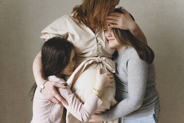 Schwangere Frau umarmt ihre Töchter zu Hause - EYAF01571