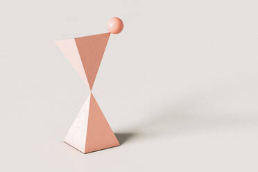 Rosa abstrakte Pyramiden mit einer Kugel balancieren auf der Oberseite gegen cremefarbenen Hintergrund - GCAF00117