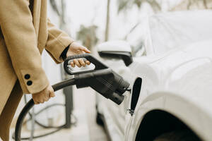 Frau lädt Elektroauto an der Tankstelle auf - GMCF00114