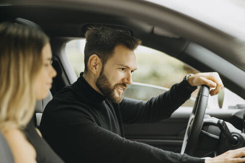 Gut aussehender Mann mit Freundin im Auto während einer Autoreise - GMCF00117