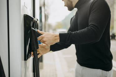 Mann hält elektrisches Ladegerät am Bahnhof - GMCF00122