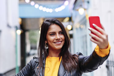 Schöne Frau lächelnd während der Aufnahme selfie auf Handy in der Stadt - ASGF00206