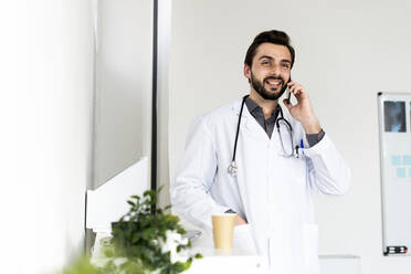 Smiling male healthcare talking on smart phone while looking away - GIOF12250