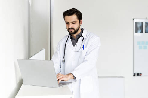 Gut aussehender männlicher Arzt mit Laptop im Krankenhaus - GIOF12251
