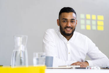 Handsome male entrepreneur sitting at desk in office - GIOF12281