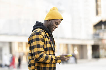 Junger Mann mit Strickmütze bei der Benutzung eines Smartphones - JCCMF01841