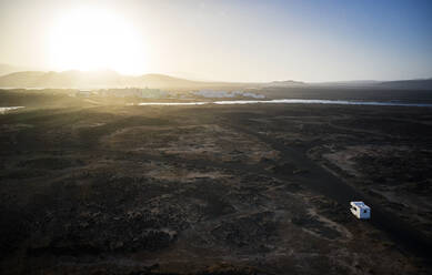 Spanien, Kanarische Inseln, Luftaufnahme eines Wohnmobils, das der aufgehenden Sonne auf einer Schotterstraße auf der Insel Lanzarote entgegenfährt - CVF01688