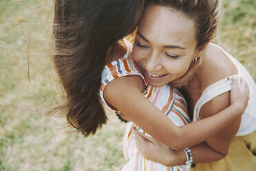 Smiling mature woman embracing daughter - AZF00240