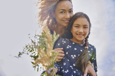 Lächelnde Mutter und Tochter mit einem Strauß Wildblumen - AZF00259
