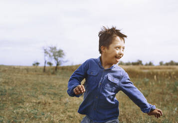 Boy with down syndrome running while looking back over shoulder - AZF00264