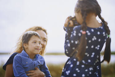 Girl photographing mother and brother - AZF00271