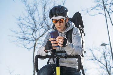 Delivery man leaning on bicycle while using smart phone - DAMF00769