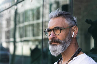 Hipster-Mann mit In-Ear-Kopfhörern schaut weg - PNAF01363