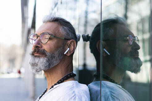 Hipster man with eyes closed in front of glass - PNAF01364