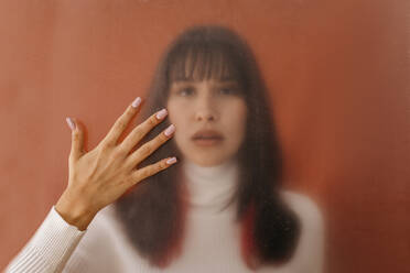 Hand touching plastic sheet with woman in background - TCEF01747