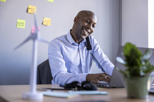 Male professional talking on landline phone while working in office - WPEF04253