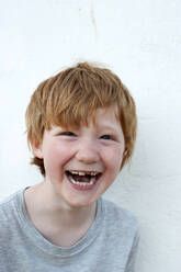 Laughing redhead boy in front of white wall - GISF00792