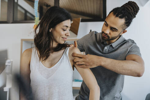 Physiotherapist examining shoulder of female patient in practice - MFF07687