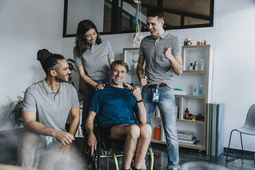 Physiotherapists cheering patient sitting on wheelchair in practice - MFF07714