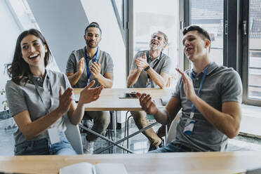 Happy male and female trainees clapping while sitting in training class - MFF07762