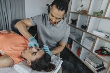 Physiotherapeutin bei der Behandlung des Kiefermuskels eines Patienten in einer Arztpraxis - MFF07798