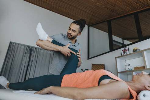 Physiotherapist treating knee of female patient in medical practice - MFF07805