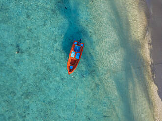 Luftaufnahme eines roten Bootes auf dem türkisfarbenen Wasser des Kaafu-Atolls, Malediven - KNTF06225