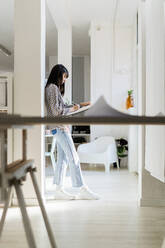 Businesswoman writing while leaning on column at office - GIOF12356